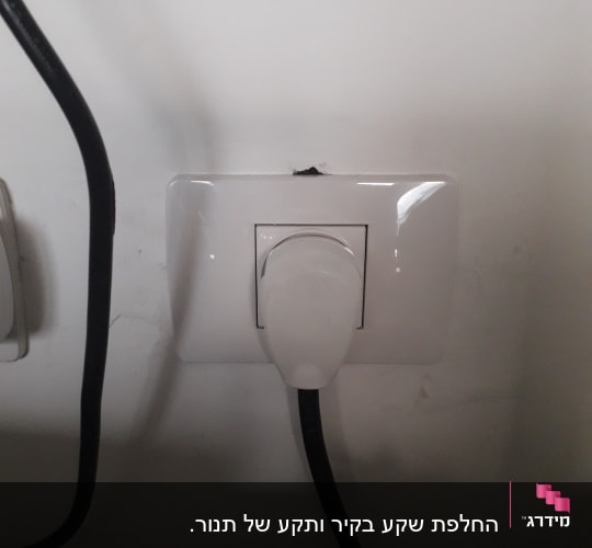 שקע חשמל עם תקע מחובר לקיר לבן